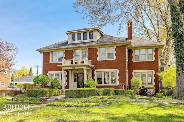 georgian-style home with a chimney, a front yard, and brick siding