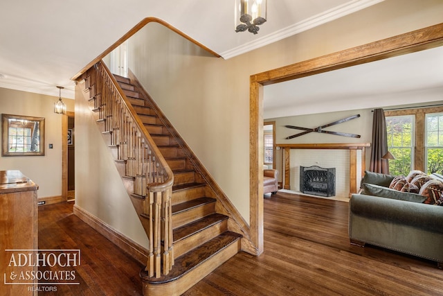 stairway featuring baseboards, ornamental molding, hardwood / wood-style flooring, and a fireplace