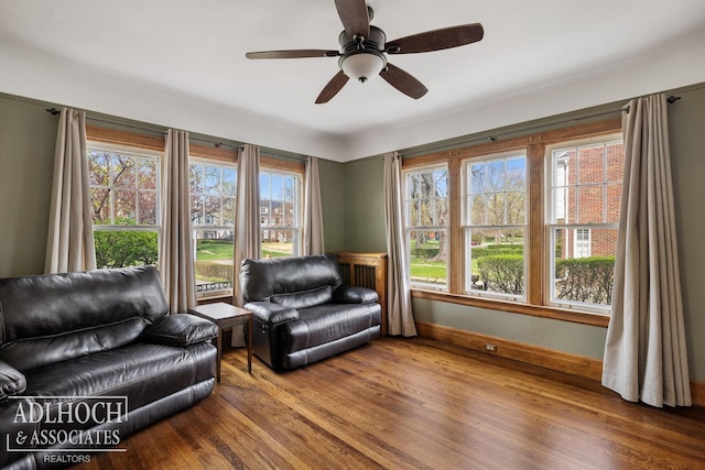sitting room featuring a ceiling fan, baseboards, plenty of natural light, and wood finished floors