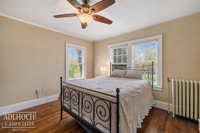 bedroom featuring baseboards, multiple windows, radiator heating unit, and hardwood / wood-style flooring