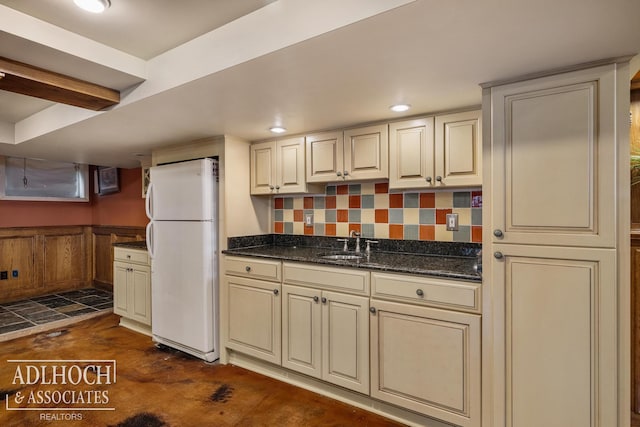 kitchen with freestanding refrigerator, a sink, concrete flooring, and cream cabinetry