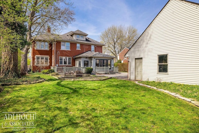 back of house with a lawn, a patio area, and brick siding