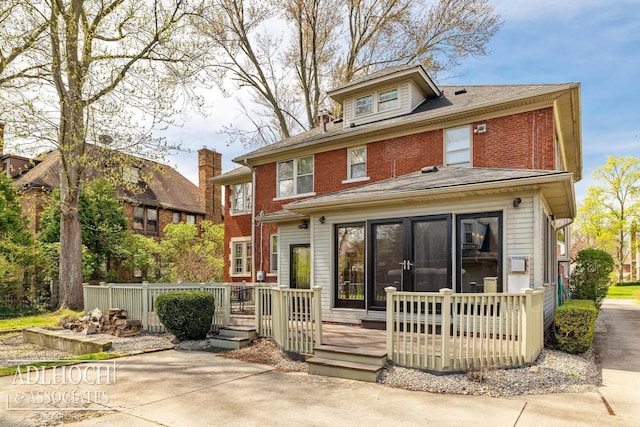 rear view of house featuring brick siding and a deck