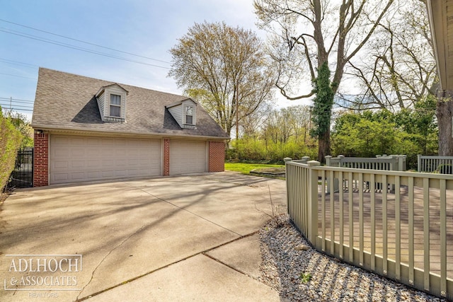 exterior space featuring a garage, an outdoor structure, a shingled roof, and brick siding
