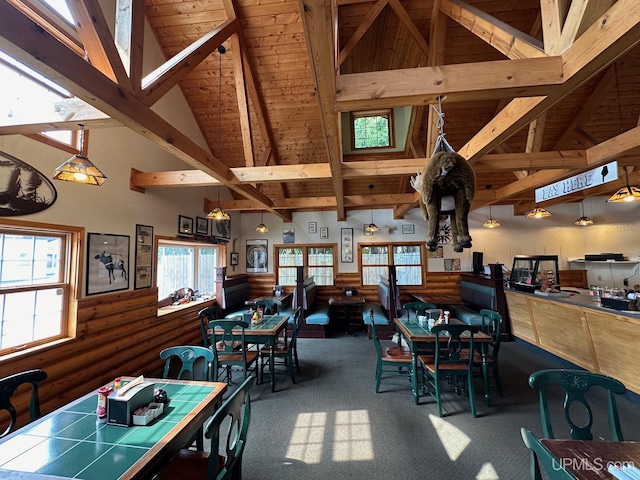 dining space with wainscoting, beam ceiling, wooden ceiling, carpet floors, and high vaulted ceiling