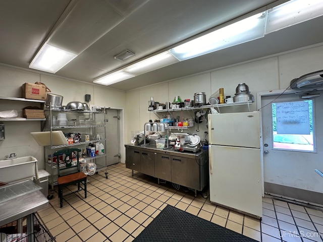 kitchen featuring freestanding refrigerator, open shelves, stainless steel countertops, and light tile patterned floors