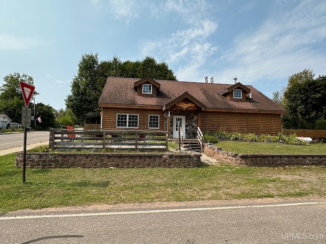 view of front of house with fence, log siding, and a front yard