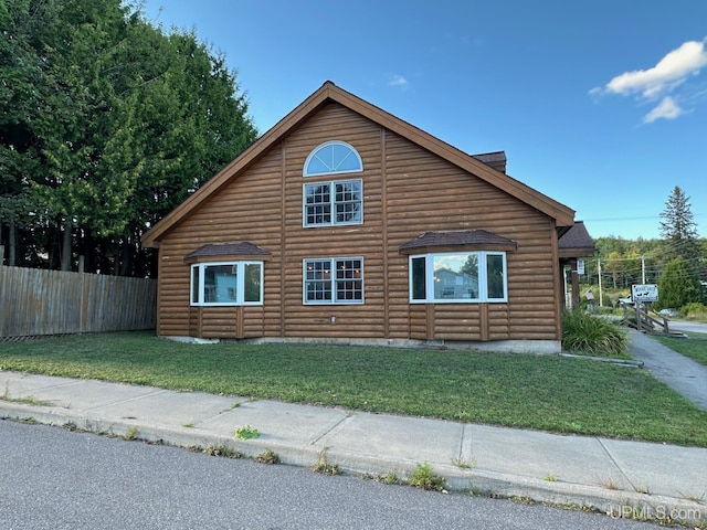 view of side of property featuring a yard, fence, and faux log siding