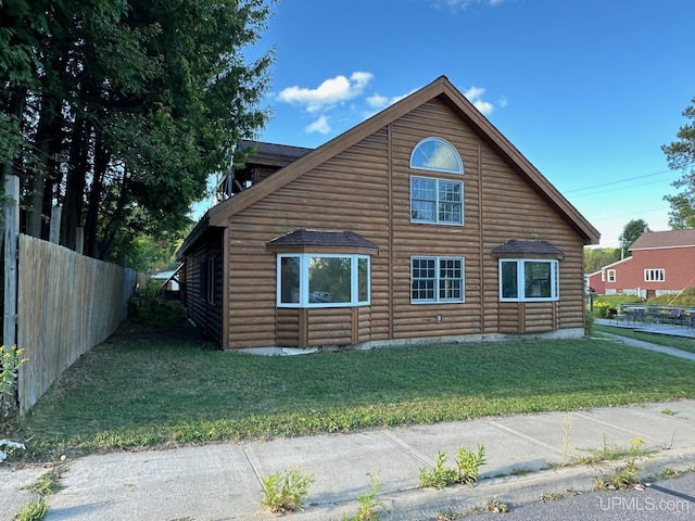 view of side of property with fence, faux log siding, and a yard