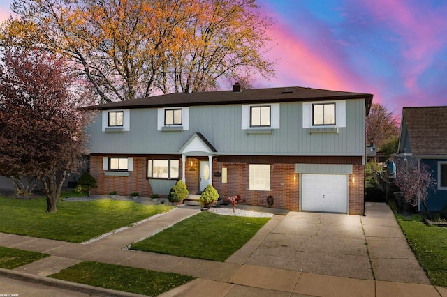 view of front of property with a yard, brick siding, an attached garage, and driveway