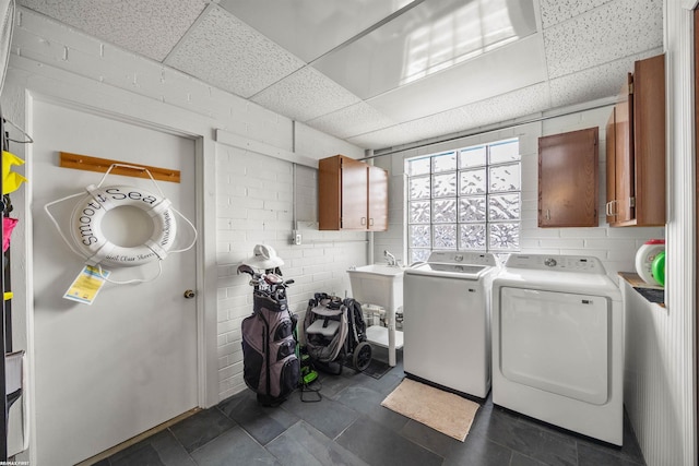 clothes washing area with a sink, cabinet space, and washer and dryer