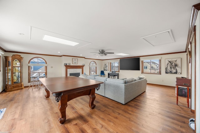 living room with a ceiling fan, ornamental molding, wood finished floors, and a fireplace