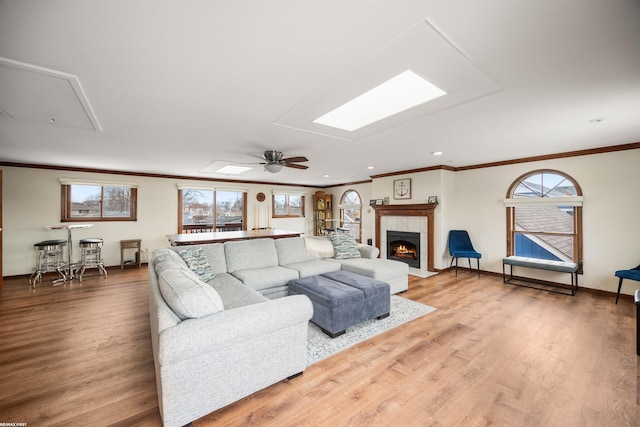 living room featuring crown molding, attic access, wood finished floors, and a tiled fireplace