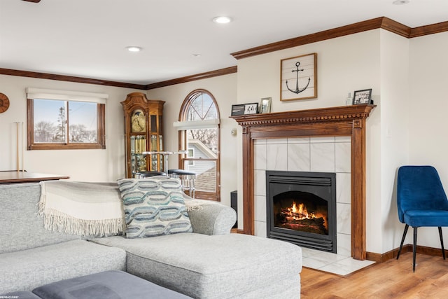 living room featuring a fireplace, recessed lighting, baseboards, wood finished floors, and ornamental molding