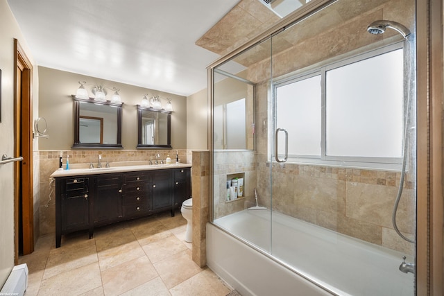 bathroom featuring a sink, wainscoting, tile patterned floors, and tile walls