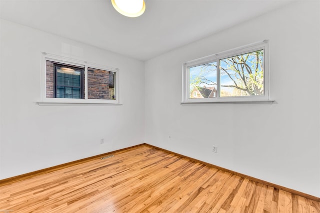 unfurnished room featuring baseboards, wood finished floors, and visible vents