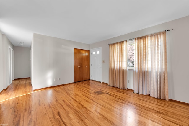 unfurnished living room featuring baseboards and light wood finished floors