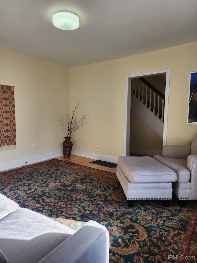 living area featuring baseboards and stairway