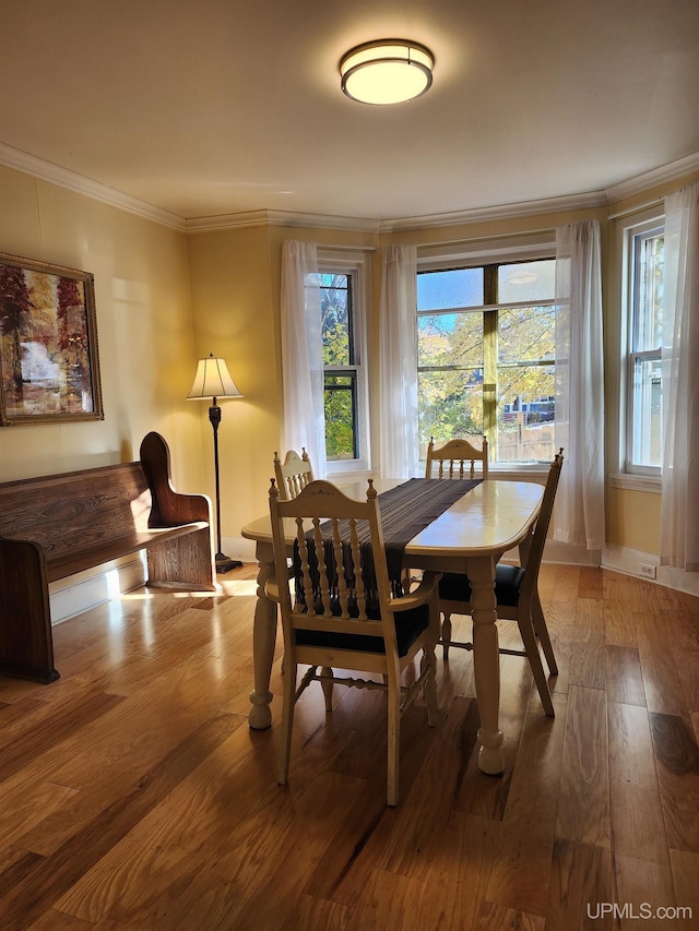 dining area with wood-type flooring, baseboards, and ornamental molding