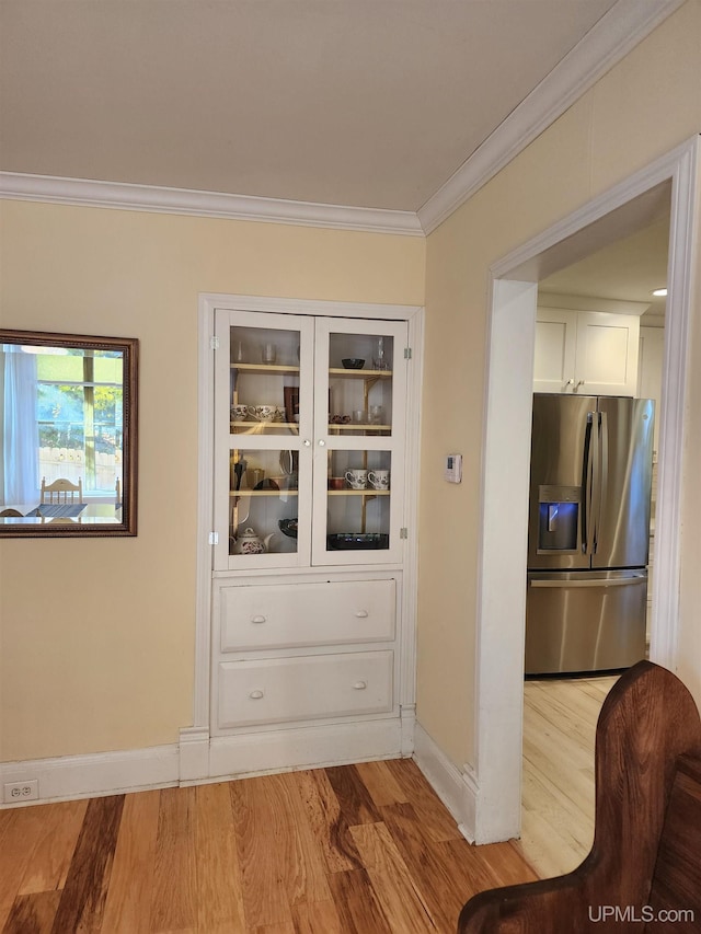 interior space with baseboards, ornamental molding, and light wood finished floors