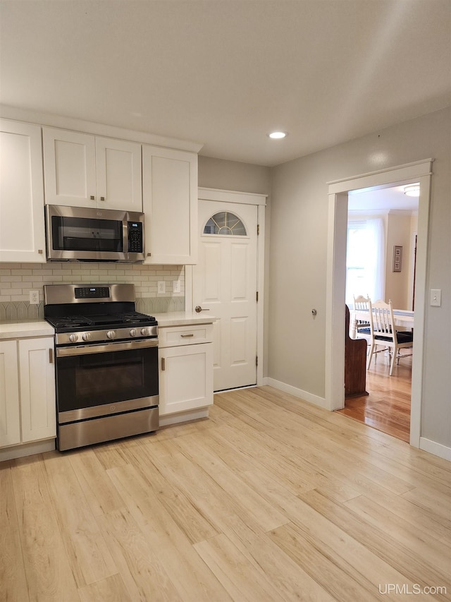 kitchen featuring light countertops, appliances with stainless steel finishes, white cabinets, and backsplash