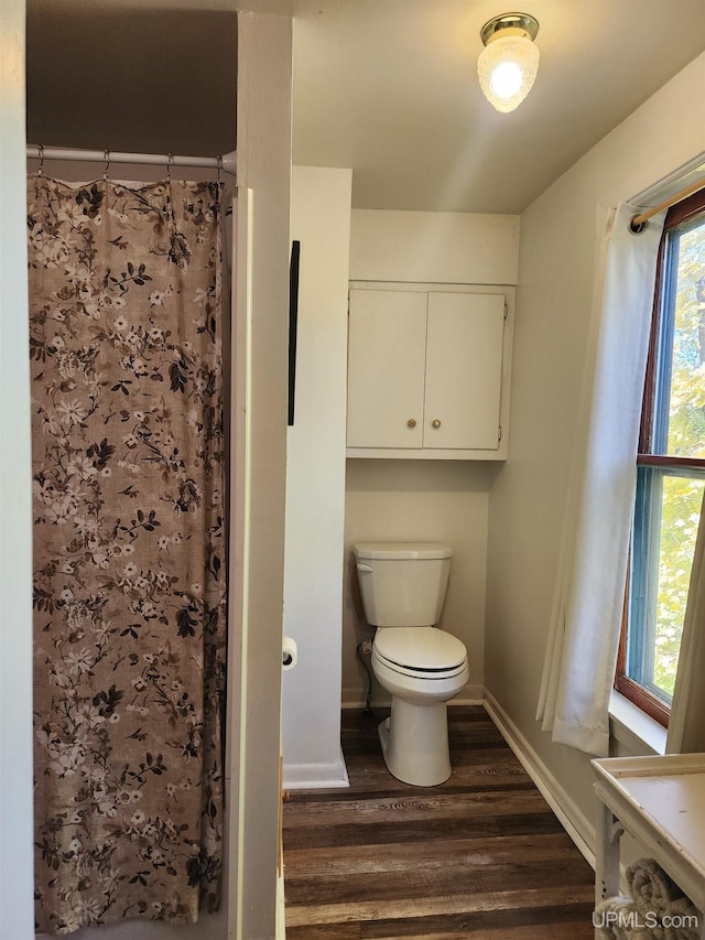 bathroom featuring baseboards, a shower with curtain, toilet, and wood finished floors