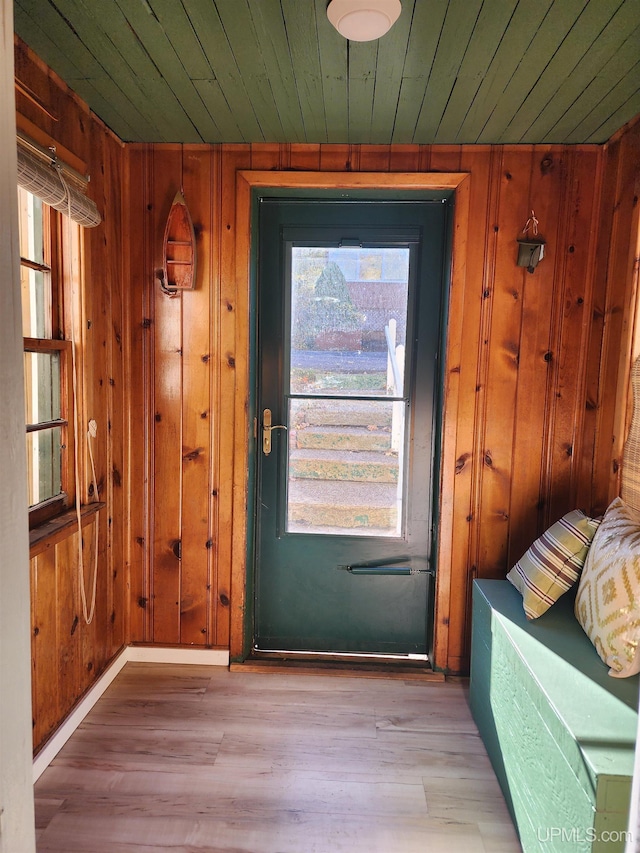 doorway to outside featuring baseboards, wood ceiling, wood finished floors, and wooden walls