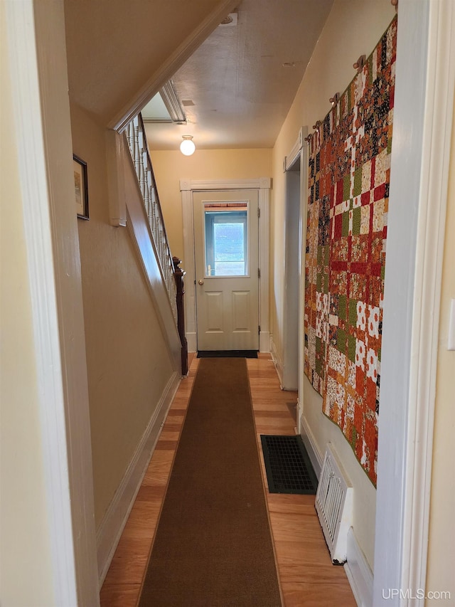 doorway featuring baseboards, visible vents, stairway, and light wood-style floors