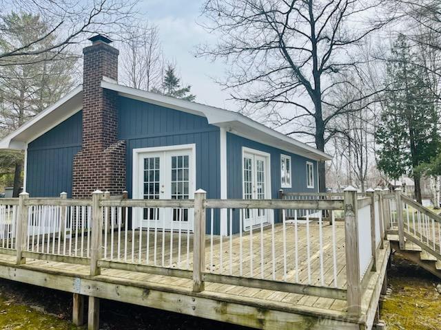back of property featuring a wooden deck, french doors, and a chimney