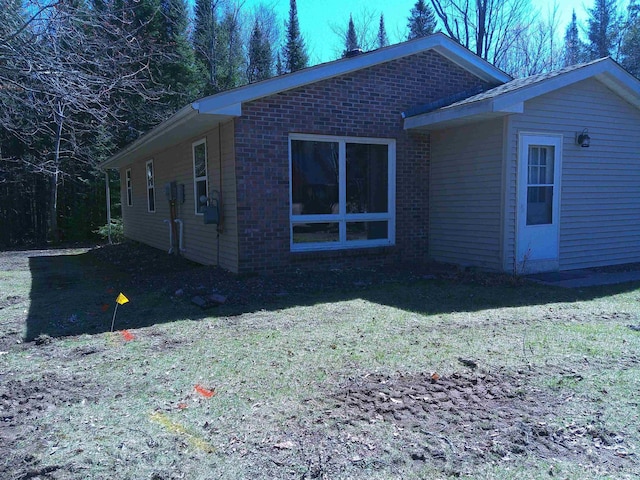 view of side of home with a yard and brick siding