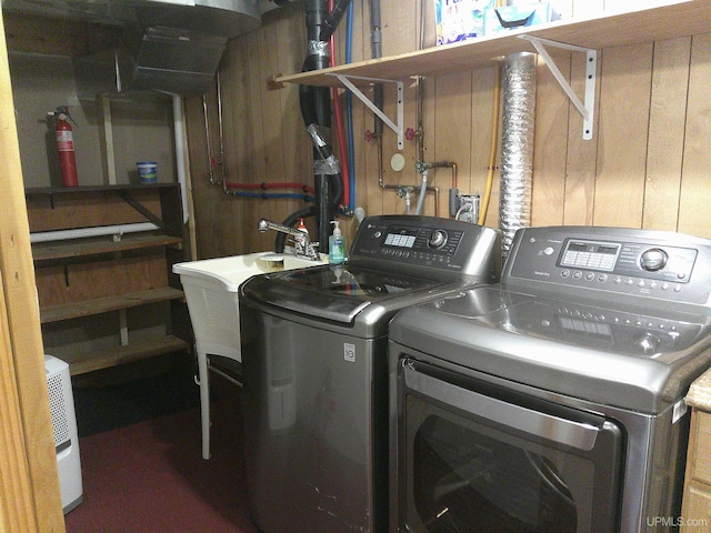 laundry room with washer and dryer, laundry area, wood walls, and a sink