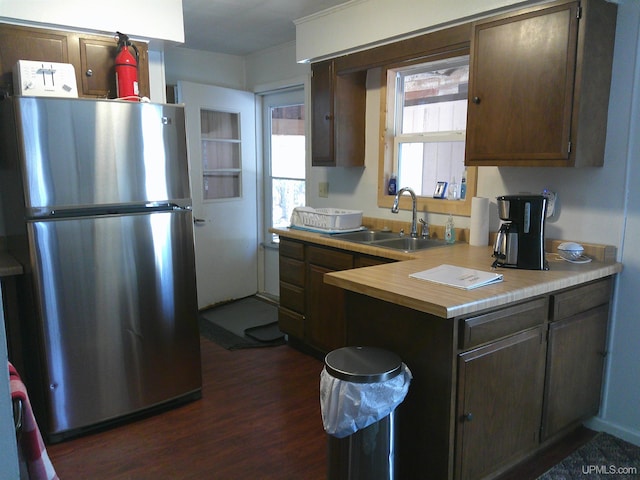kitchen with freestanding refrigerator, dark brown cabinetry, dark wood-style floors, and a sink