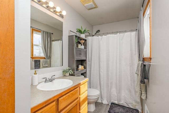 full bathroom featuring vanity, visible vents, wood finished floors, curtained shower, and toilet