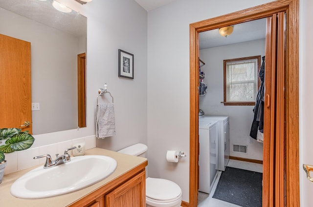 bathroom featuring independent washer and dryer, toilet, visible vents, and vanity