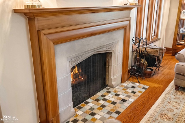 interior details with a fireplace with flush hearth and wood finished floors