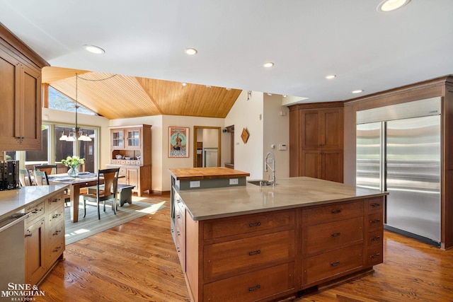 kitchen featuring wood finished floors, a sink, lofted ceiling, and stainless steel appliances