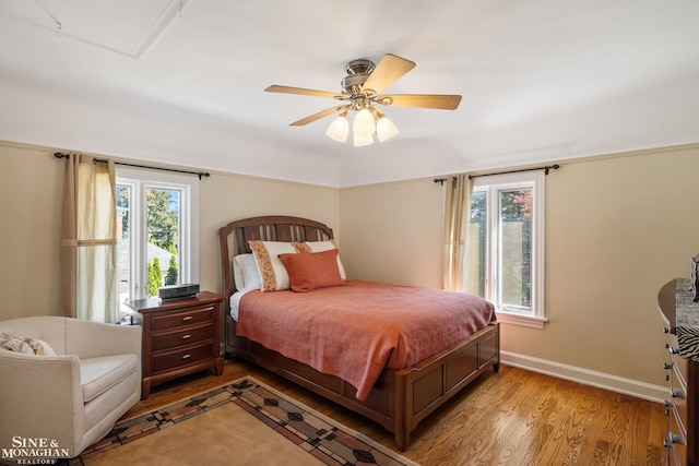 bedroom with baseboards, light wood finished floors, ceiling fan, and multiple windows