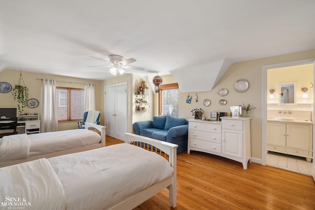 bedroom with a sink, light wood-style flooring, lofted ceiling, and multiple windows