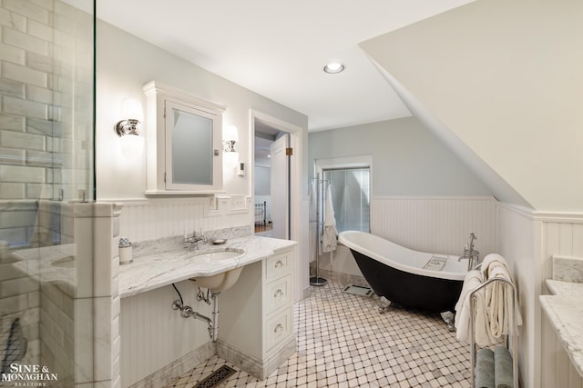 bathroom with recessed lighting, a sink, wainscoting, and a freestanding bath