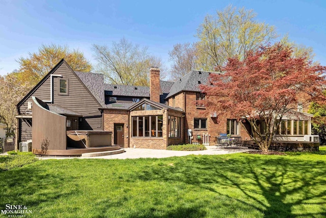 back of property featuring a patio, a chimney, a hot tub, and brick siding
