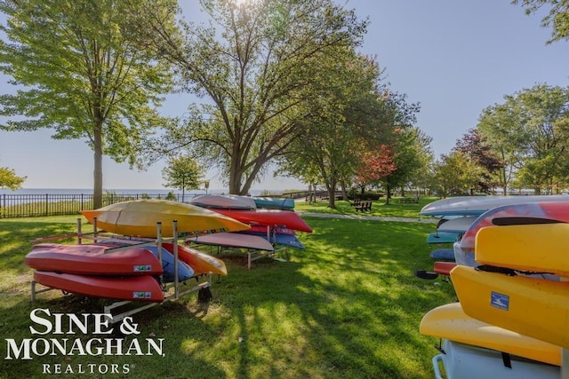 exterior space featuring a lawn, a water view, and fence