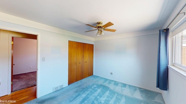 unfurnished bedroom with a closet, a ceiling fan, carpet flooring, and visible vents