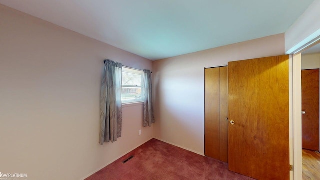 unfurnished bedroom featuring baseboards, a closet, carpet flooring, and visible vents