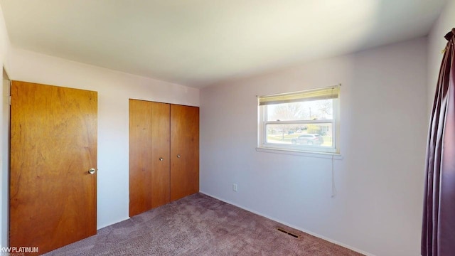 unfurnished bedroom featuring carpet floors, a closet, and visible vents