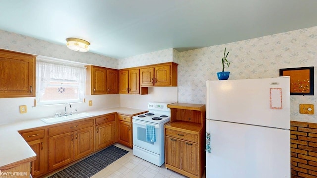 kitchen with brown cabinets, light countertops, a sink, wallpapered walls, and white appliances
