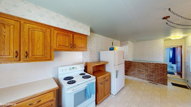 kitchen featuring brown cabinetry, visible vents, light countertops, wallpapered walls, and white appliances