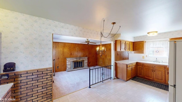 kitchen featuring a notable chandelier, a sink, light countertops, freestanding refrigerator, and wallpapered walls