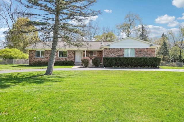 ranch-style home with curved driveway, fence, a front yard, and brick siding