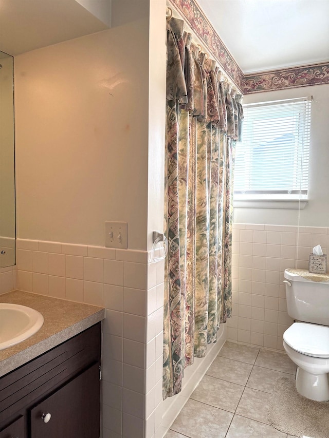full bath with tile patterned flooring, wainscoting, toilet, and tile walls