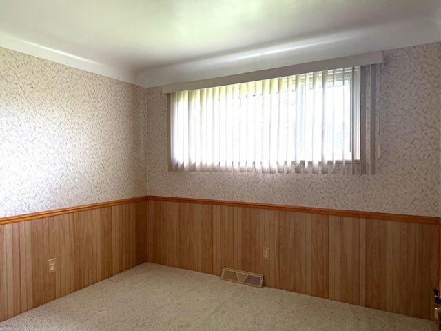 carpeted spare room featuring visible vents, wainscoting, and a wealth of natural light